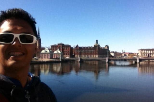 Eurail customer testimonials | Man smiling with the European architectures and a bridge in the background
