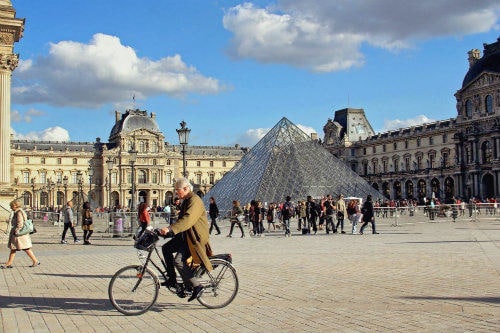 Everything about Eurail | Old man on the bicycle passing by the Louvre museum in Paris, France